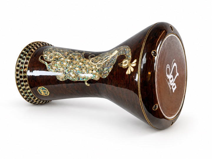 Sala Amber Peacock Sombaty darbuka på sin sida, som visar det Sala-märkta trumskinnet och ett blekt påfågelmotiv på en mörk bärnstensbrun mosaikbakgrund.