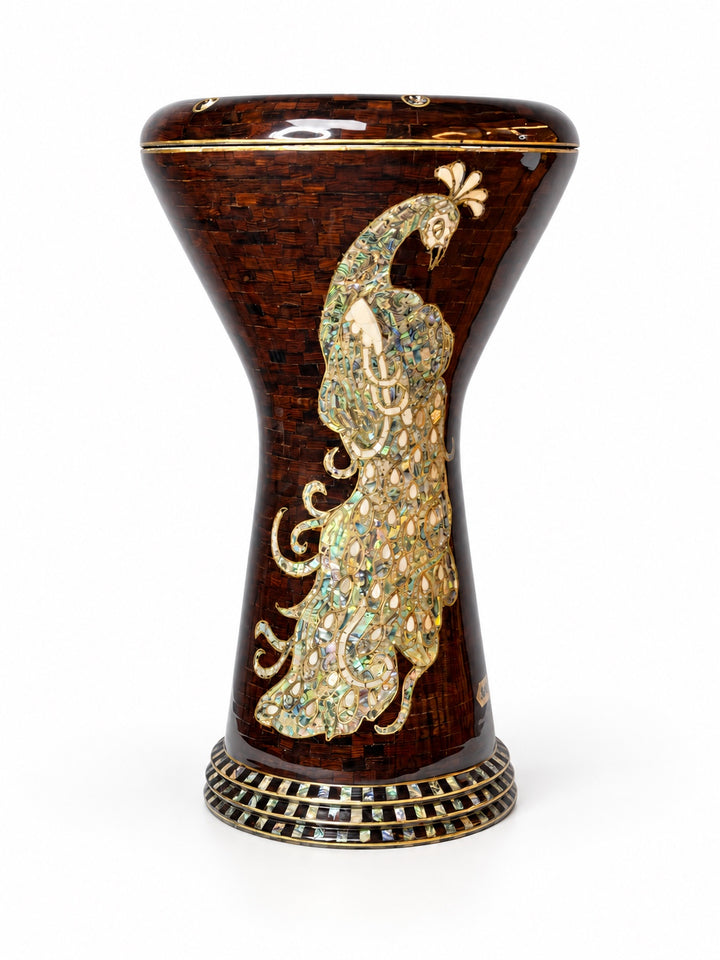 Sala Amber Peacock Sombaty darbuka som står upprätt och visar ett blekt påfågelmotiv på en mörk bärnstensbrun mosaikbakgrund.
