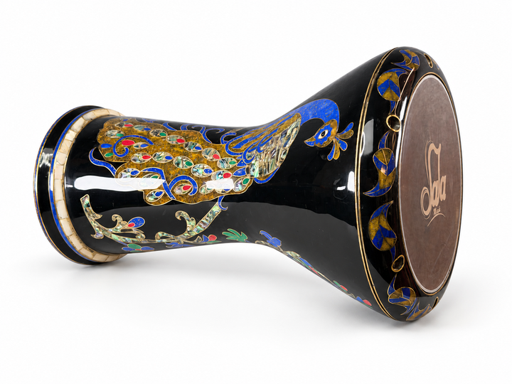 Sala Midnight Peacock Sombaty darbuka på sin sida, som visar det Sala-märkta trumskinnet och en blå- och guldpåfågel med färgglada svansdetaljer på en mörk finish.