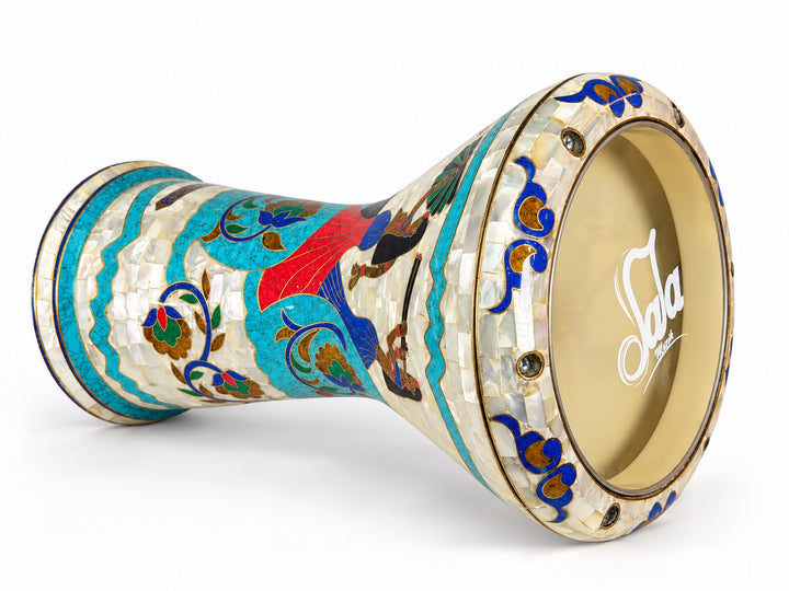 Sala Nile Muse Sombaty darbuka på sin sida, som visar det Sala-märkta trumskinnet och egyptisk-inspirerade figurer, turkosa bårder och färgglada blommiga rullar.